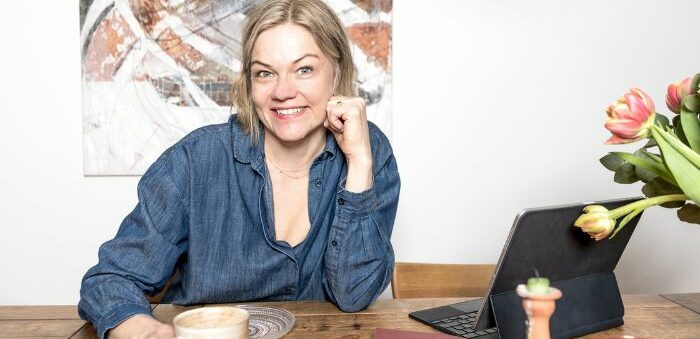 SATA Innovationsin valmentaja Anna Stenberg hymyilee kameralle kahvikuppi kädessä.